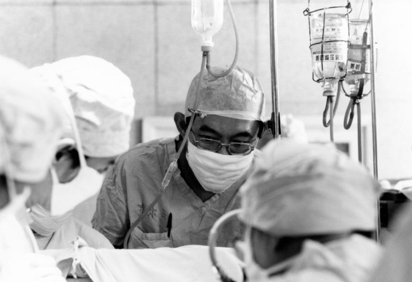 Black and white photo of Dr. Chang dressed in medical gear performing a surgery