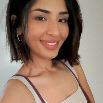 Photograph of a South Asian woman with short black hair wearing a tank top smiling towards the camera.