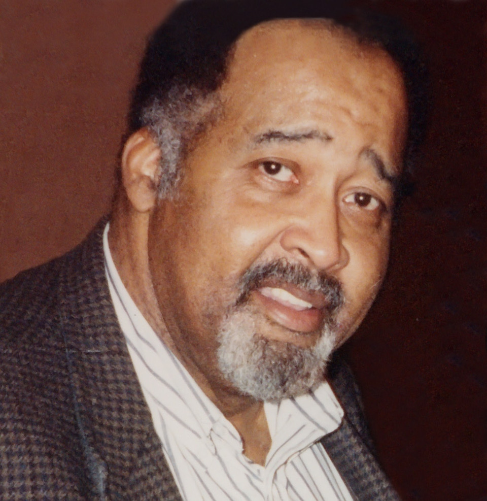 Photograph of Jerry Lawson. He has brown skin, black hair which is slightly greying on the side, and a beard. He is wearing a suit and smiling softly.