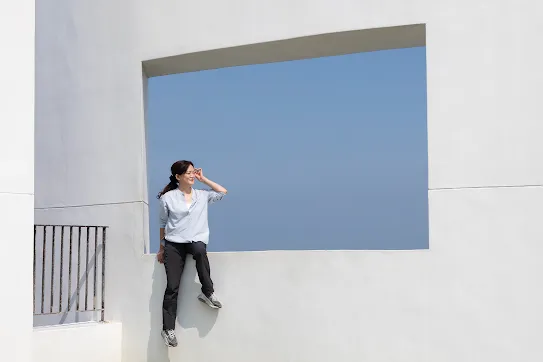 Googler Melody Chang sits in front of wall that overlooks blue sky in Changhua County Taiwan