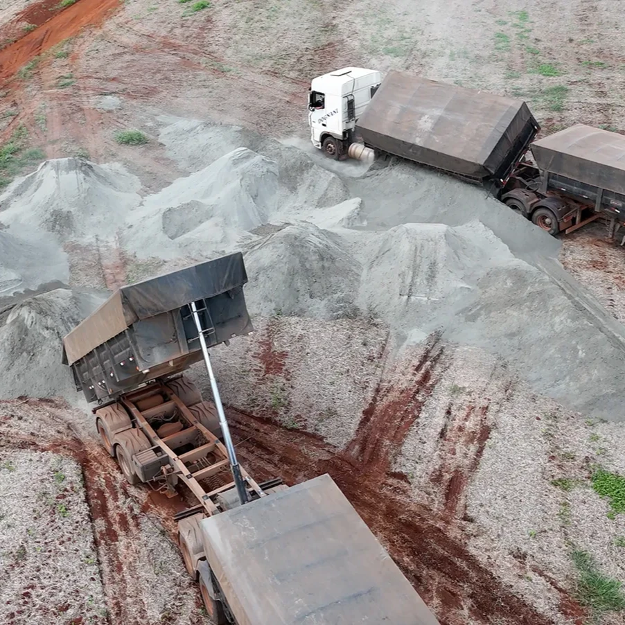 Two construction trucks crush rocks in a gravel pit