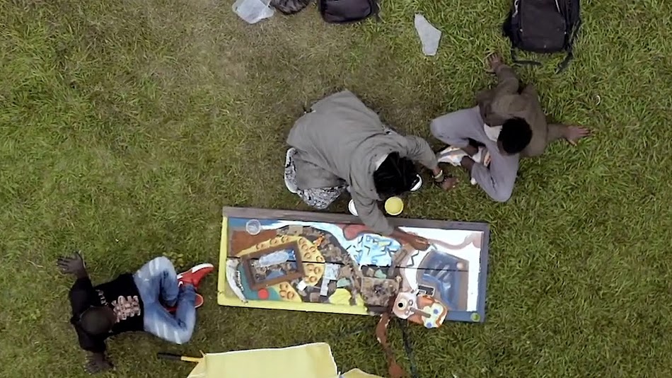 Aerial image of Congolese artist Mugabo working with friends on his mixed media piece.