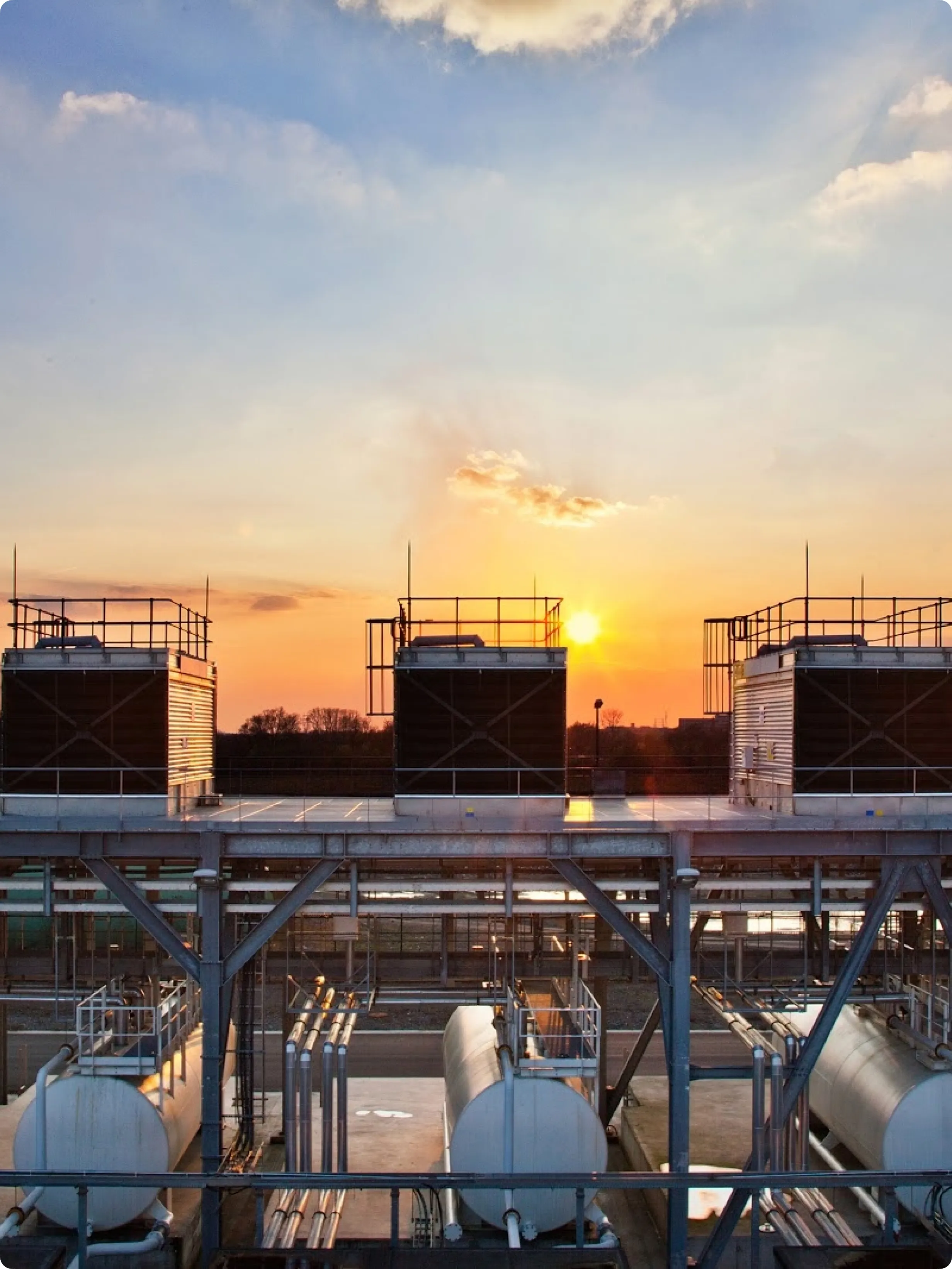 Storage tanks on top of a data center with the sun setting in the background