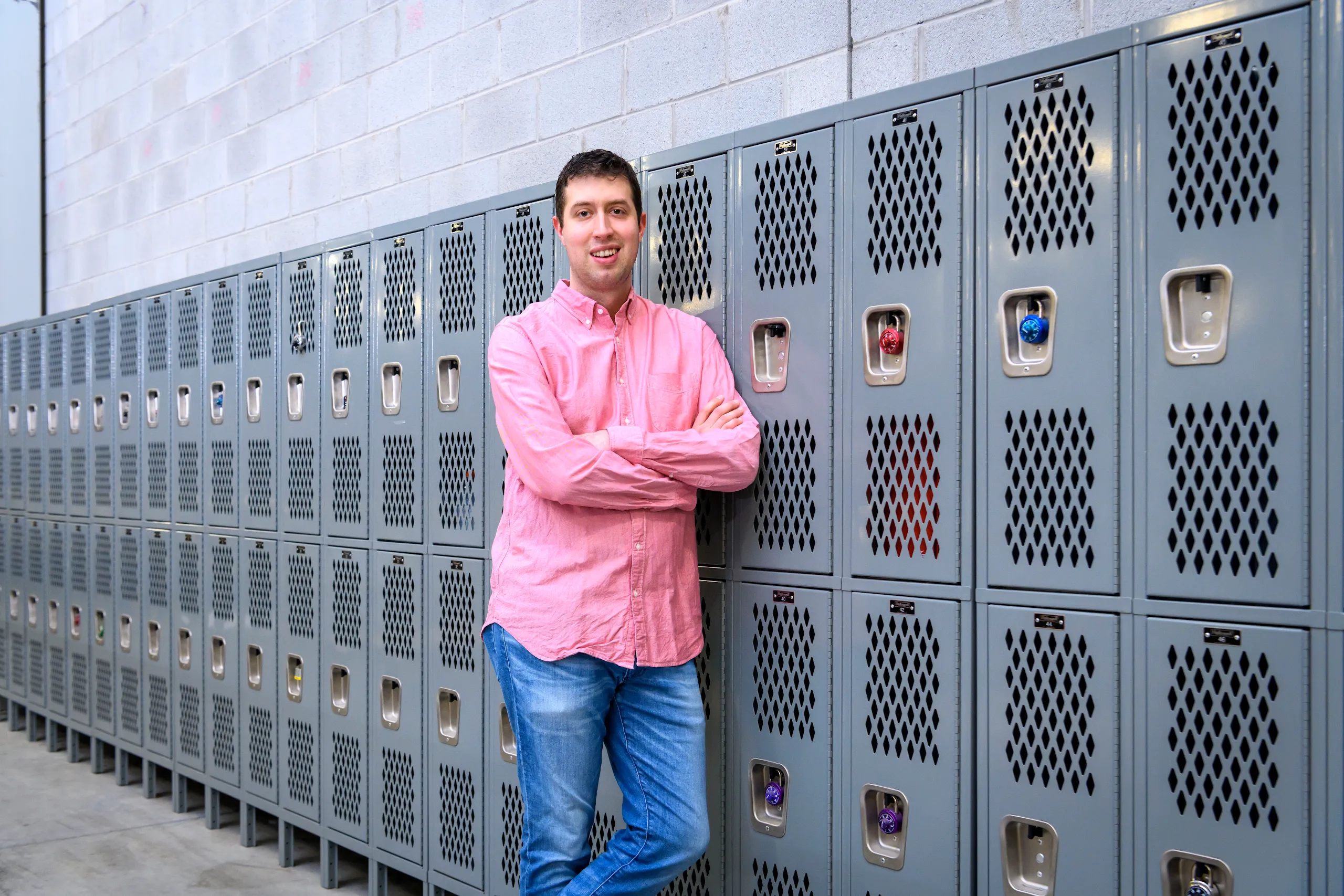 Photograph of a man with arms crossed standing against lockers in a Google facility.