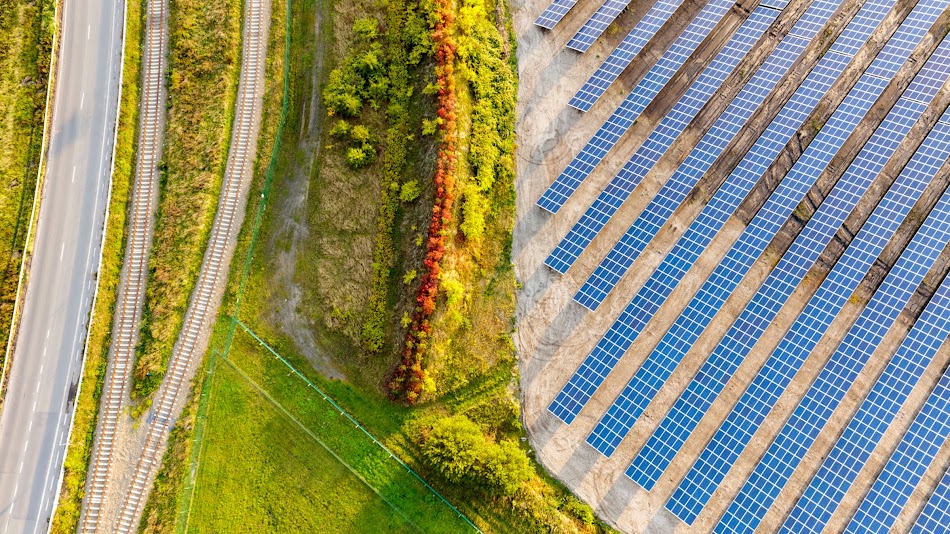 Vista aérea de un campo situado junto a varias filas de paneles solares.
