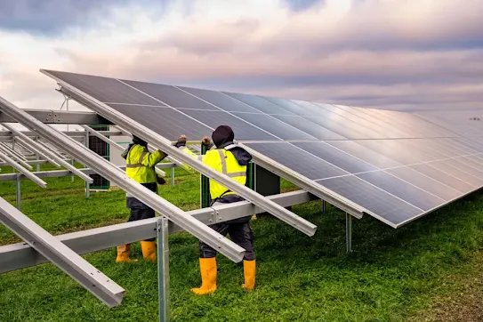 A team of solar panel installers work together on placing a panel into place on a solar farm in Fredericia, Denmark, in collaboration with our data center.