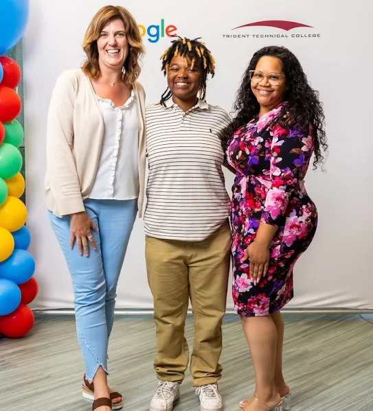 A Google Skilled Trades and Readiness Program graduate and two program managers pose for the camera after the graduation ceremony.