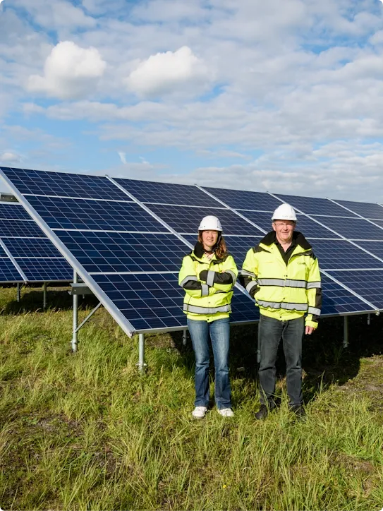 Two people wearing hardhats standing outside next to solar panels