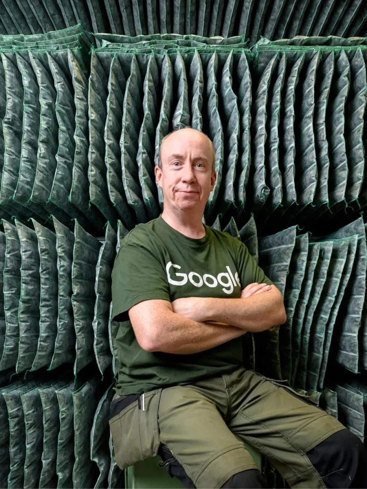 A data center technician sitting and smiling with his arms folded