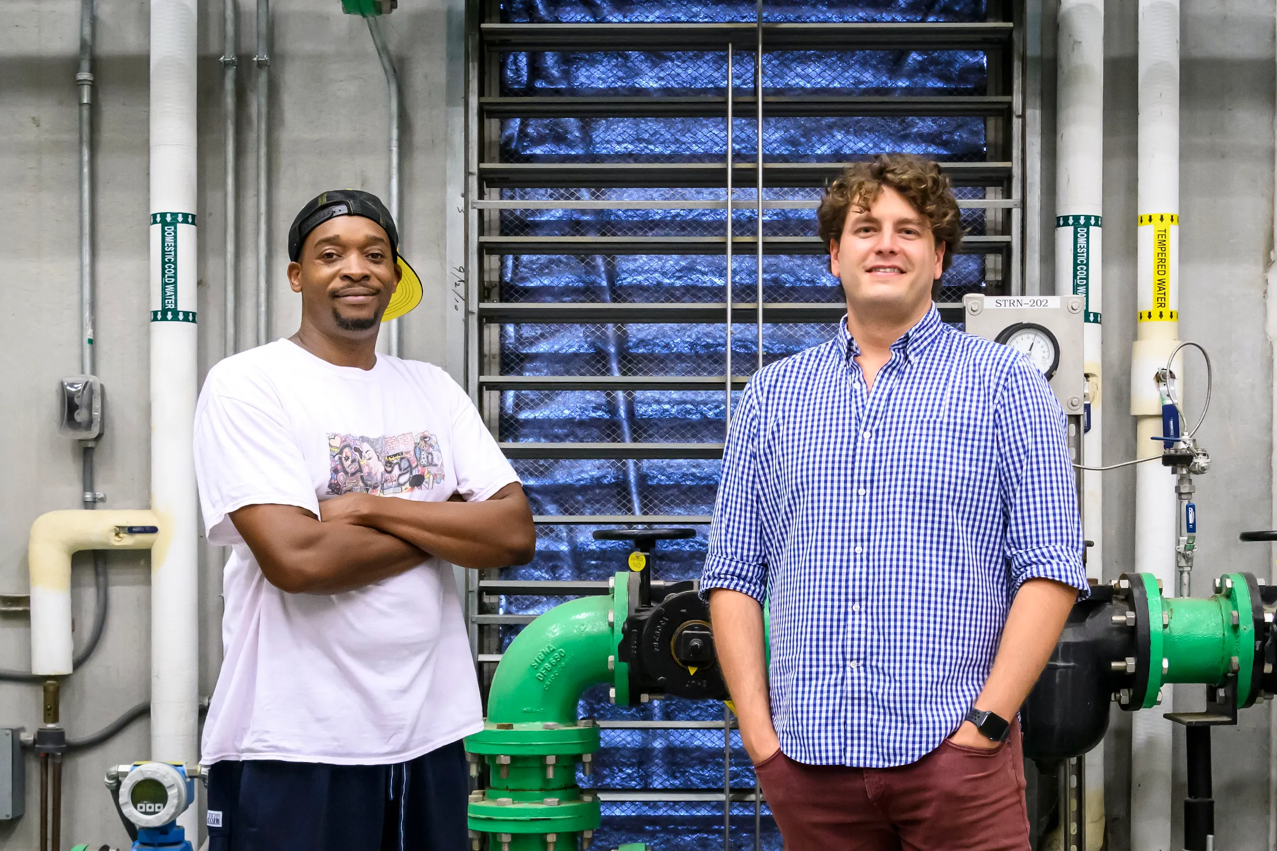 A photo of two men standing in front of pipes inside a Google facility.