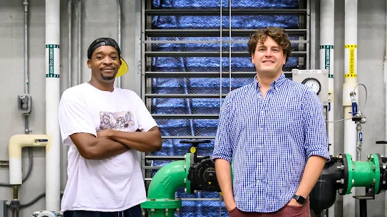 A photo of two men standing in front of pipes inside a Google facility.