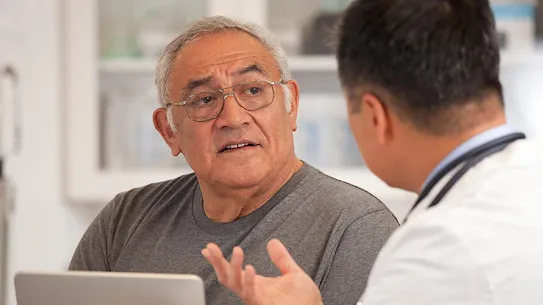 Medical professional discussing health with a senior man in a hospital setting.