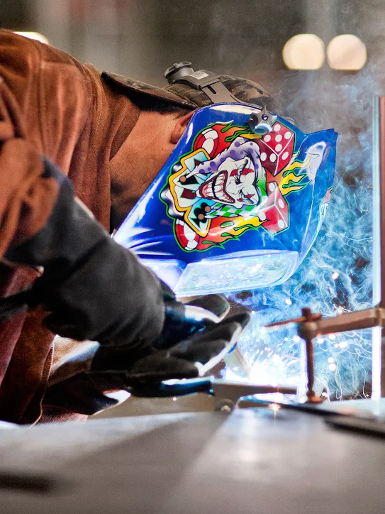 Jeff, who's an associate facilities manager in our Lenoir data center, wears a colorful welding mask while he burns some wire in a fabrication area.