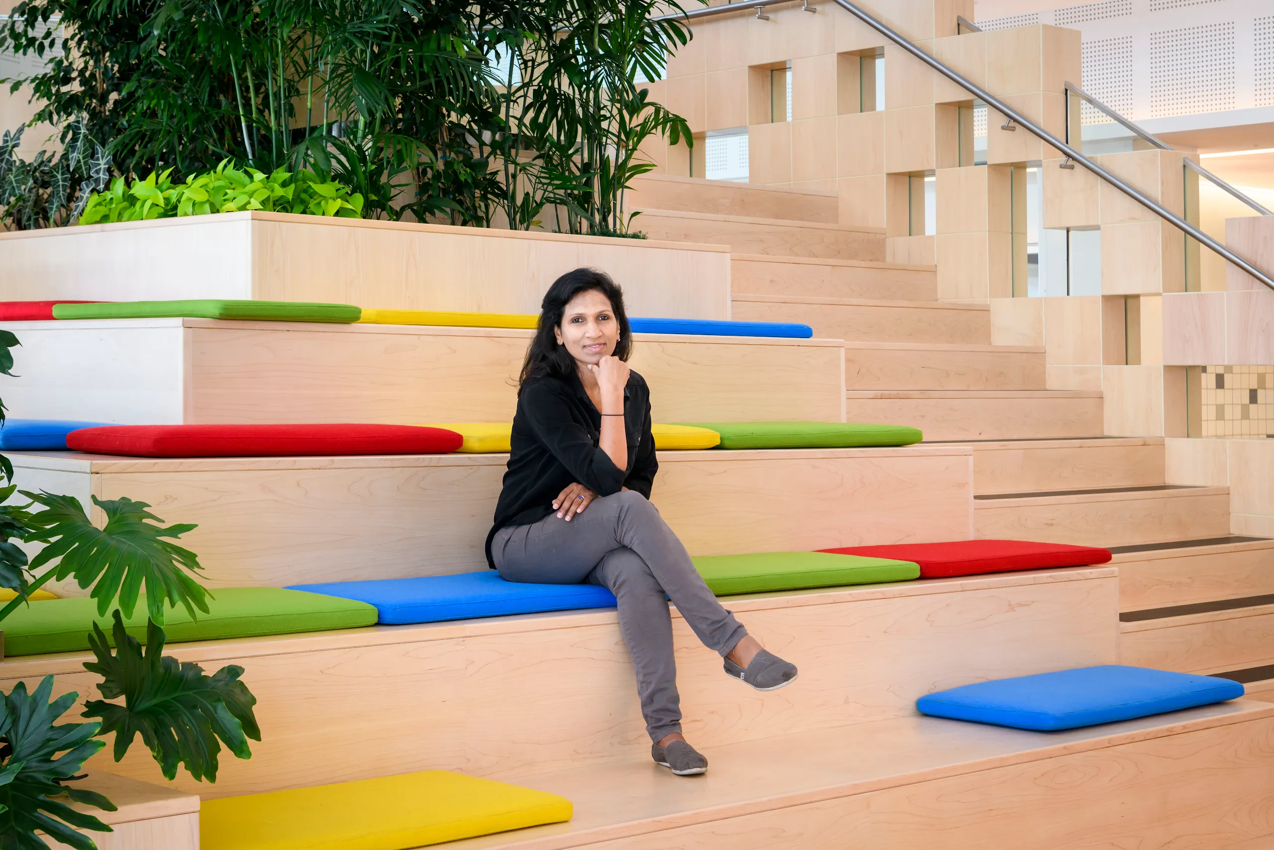 Photograph of a woman with legs crossed and hand on chin sitting on a staircase. 