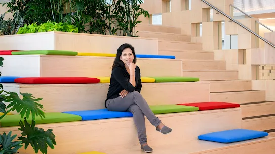 Photograph of a woman with legs crossed and hand on chin sitting on a staircase. 