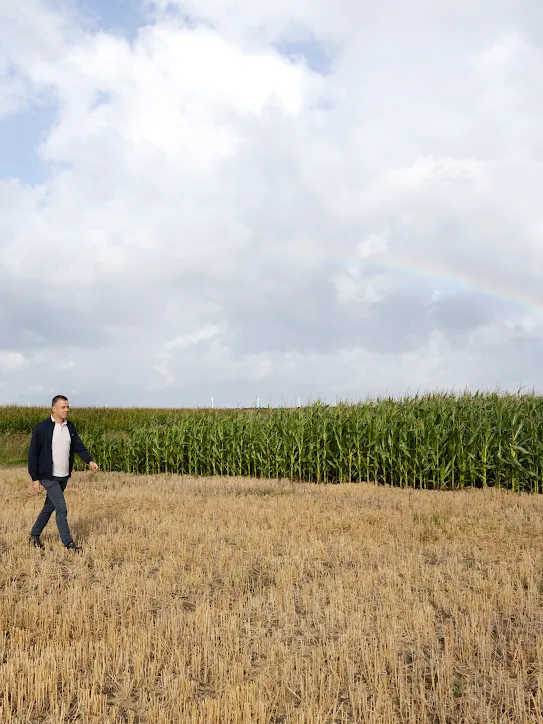 Jeroen de Schutter walking across a field with a rainbow in the background