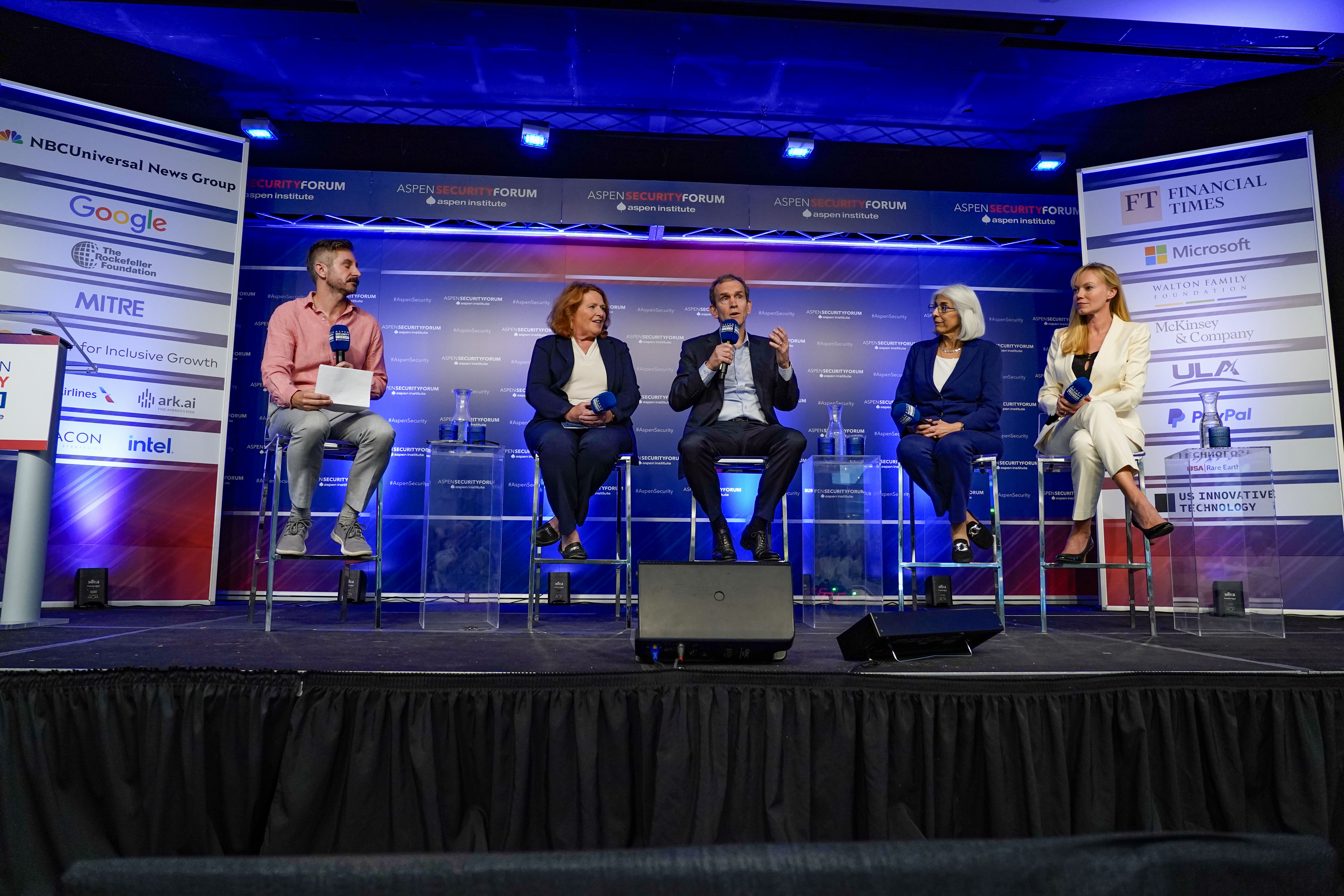 During the 2023 Aspen Security Forum, Kent Walker speaks into a microphone as three female panelists and one male moderator look at him.