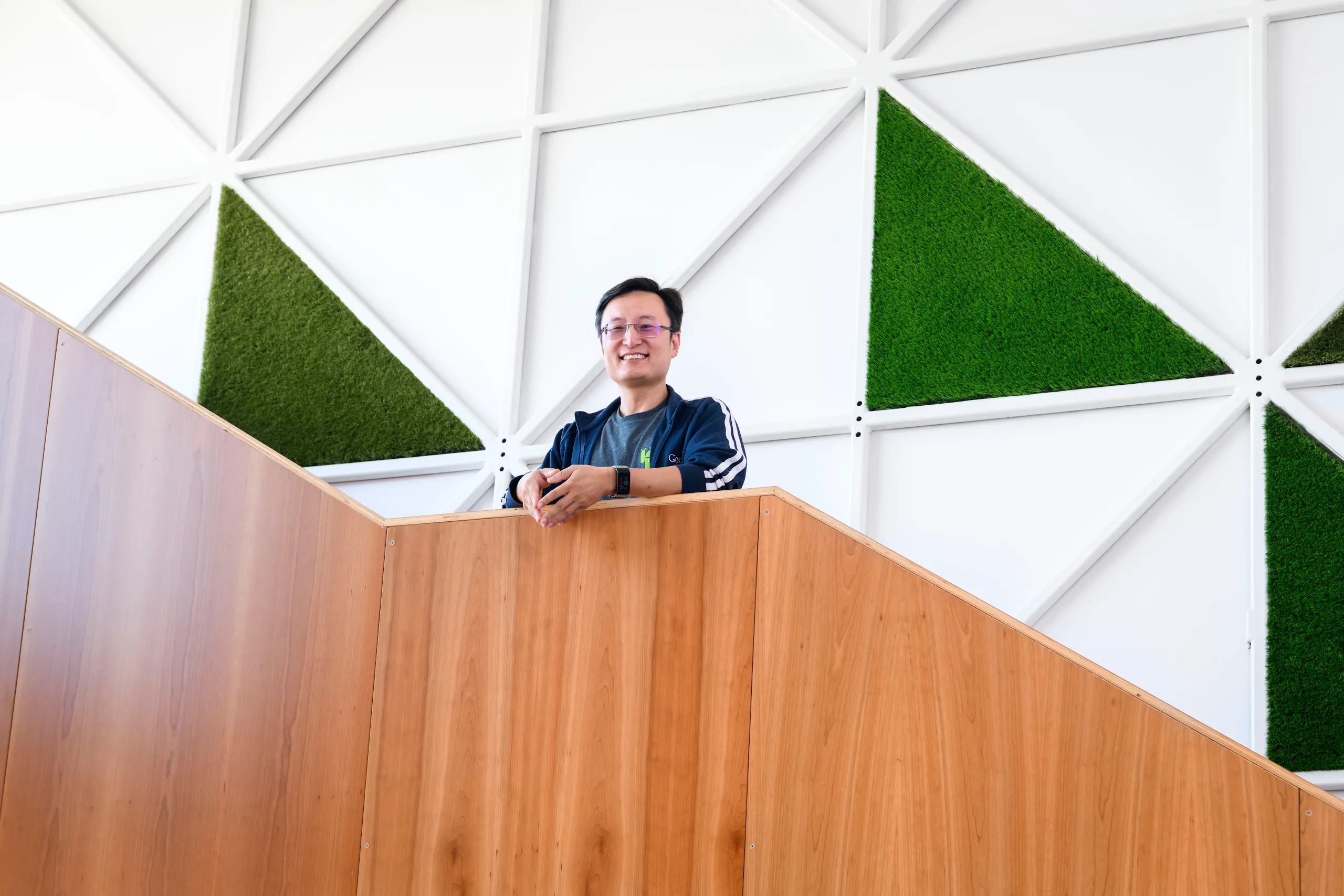 Photograph of a smiling man standing on a staircase against a graphic wall.