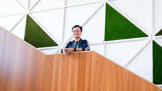 Photograph of a smiling man standing on a staircase against a graphic wall.