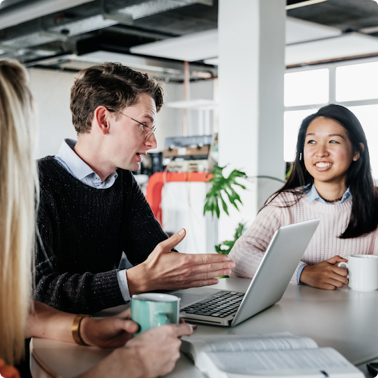 A diverse team huddles around one team member holding an open file and reviewing its contents.