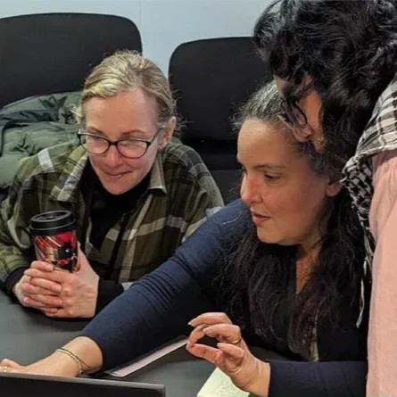 A group of three individuals working together in front of an open laptop