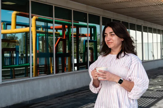 Googler Pia Quiroz carries her coffee across the Quilicura Chile data center campus with the data center pipes reflected in the window behind her