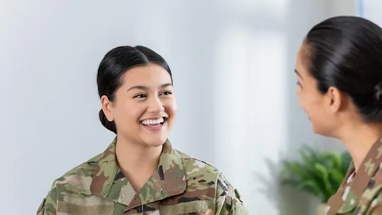 Two servicewomen chatting in a military setting.