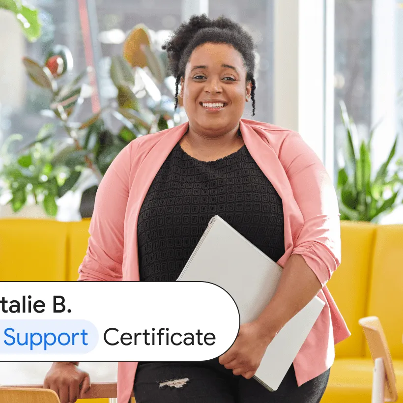 Natalie B., an IT Support Certificate graduate, stands in a brightly lit café while holding a laptop 