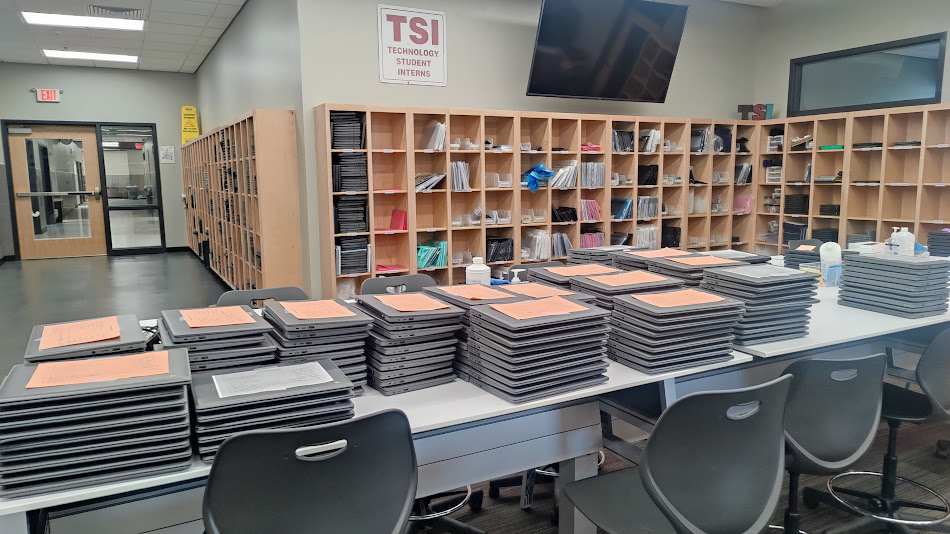 Piles de Chromebooks posés sur une table en attendant d'être réparés