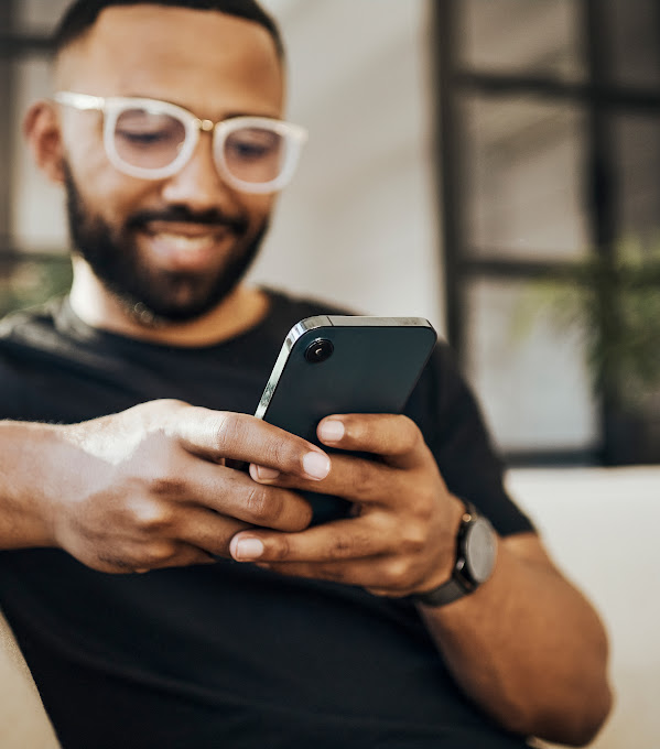 Smiling man using mobile phone while on sofa.