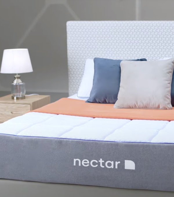 A Nectar bed in the center of a neutral colored room flanked by side tables with lamps.