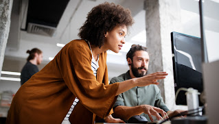 Teammates working together at a desk while looking at a computer