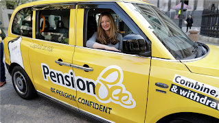 A woman with blonde hair sits in a yellow car that’s covered in PensionBee branding.