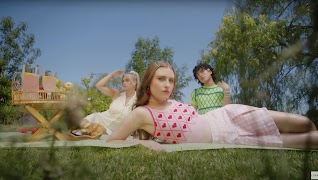 An image of three people in Cider clothing having a picnic.