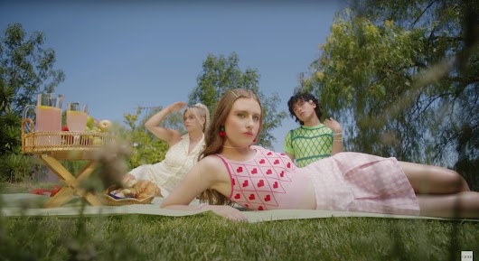 An image of three people in Cider clothing having a picnic.