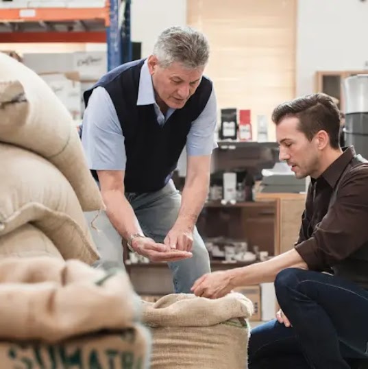 Dos hombres mirando granos de café en un taller.