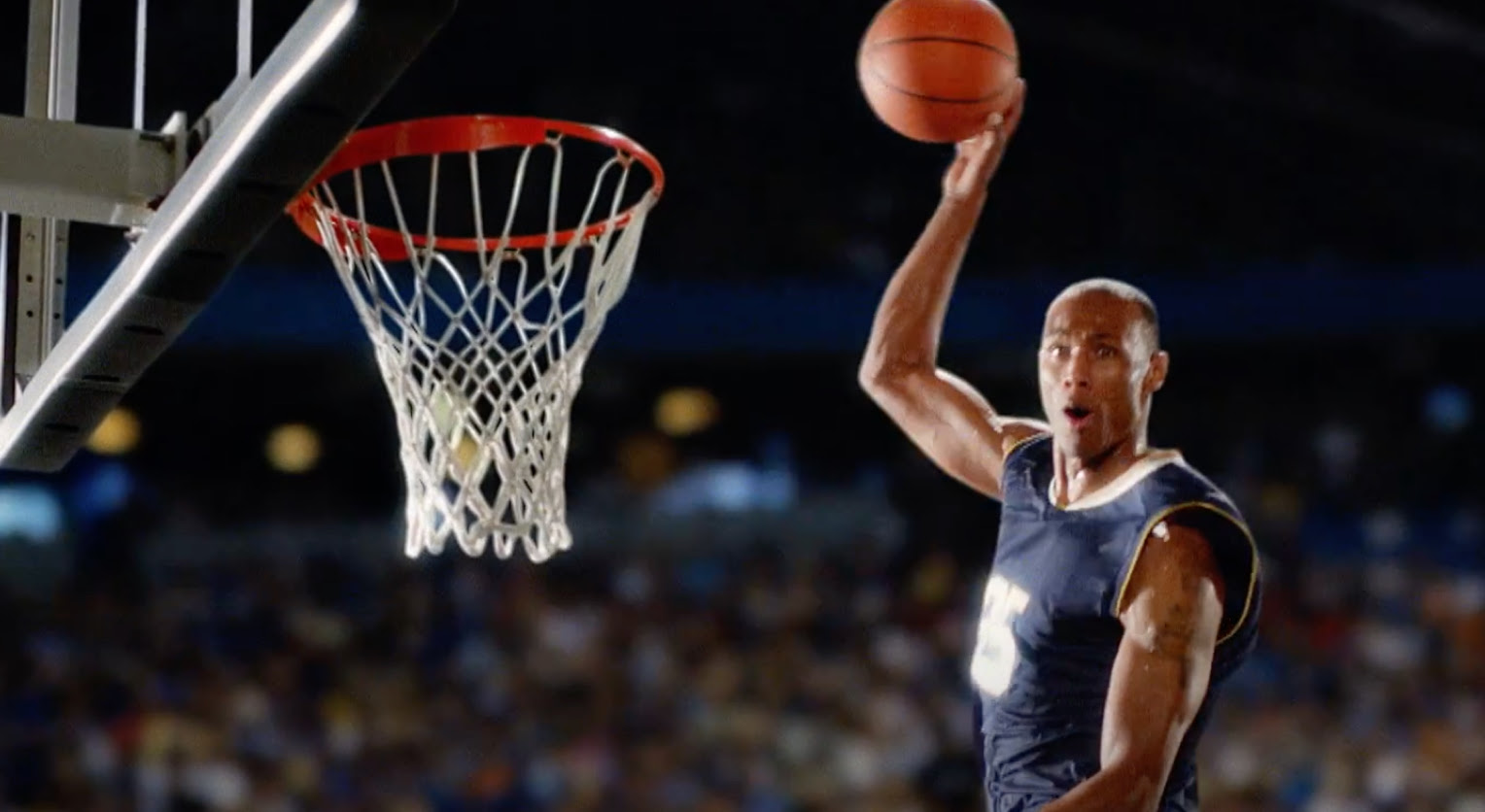 We see a basketball player dunking the ball. 