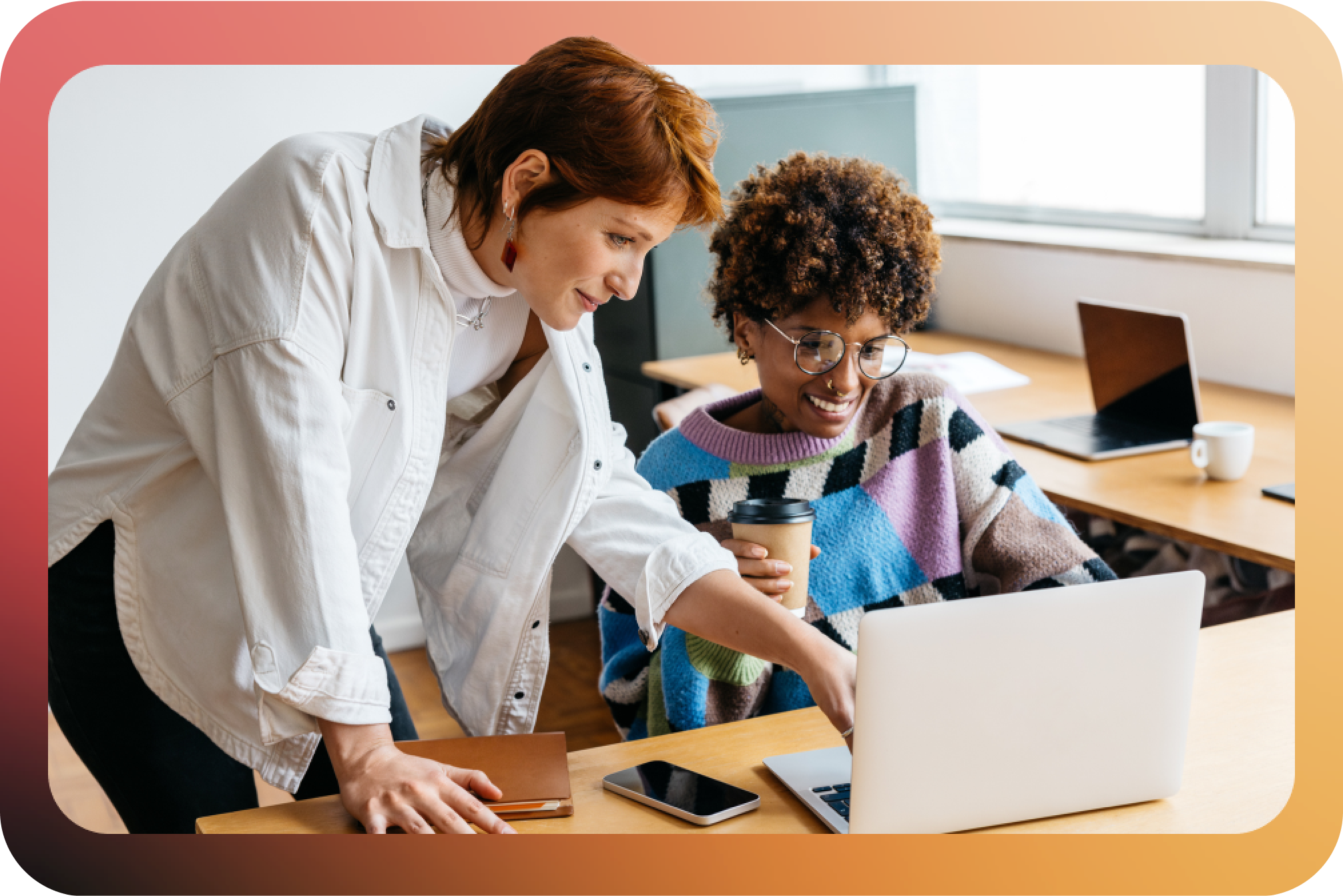 Two women looking at a laptop screen in an office setting.