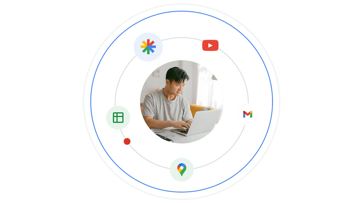 A young man uses a laptop. He’s encircled by the logos of Google products.