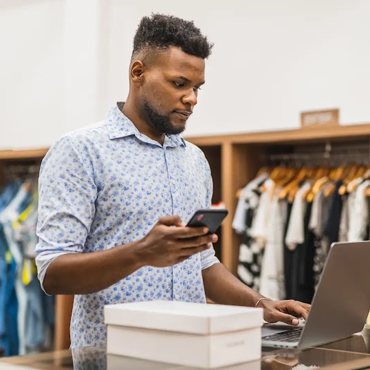 Un homme travaillant sur son ordinateur dans une boutique de vêtement