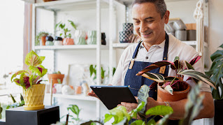 A garden store employee behind a counter with a counter with a tablet in his hand.