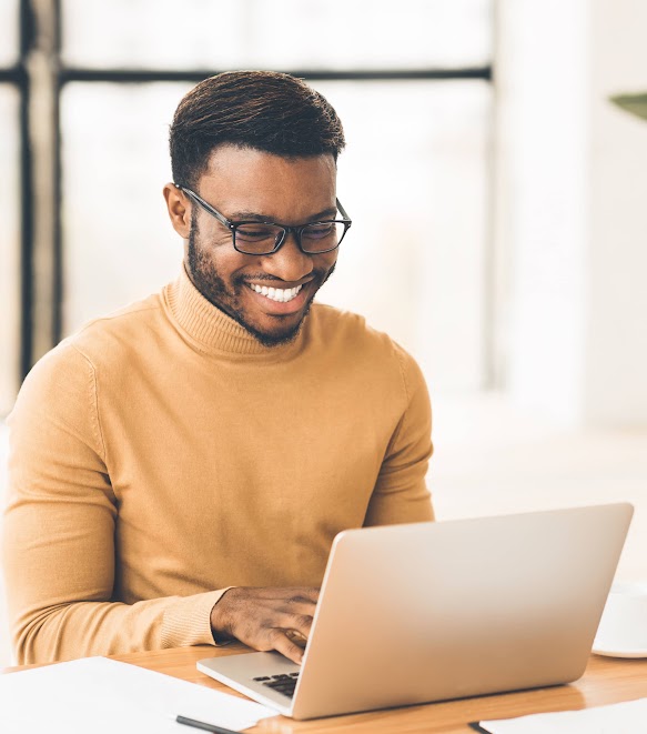 Happy man smiling and working on laptop in home office