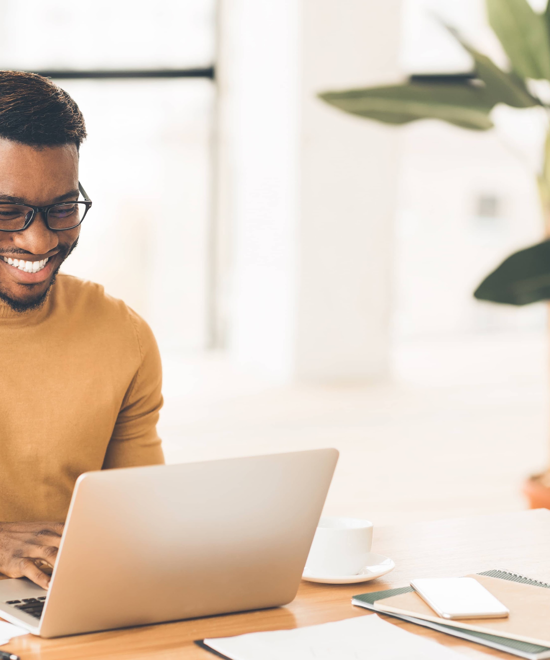 Happy man smiling and working on laptop in home office