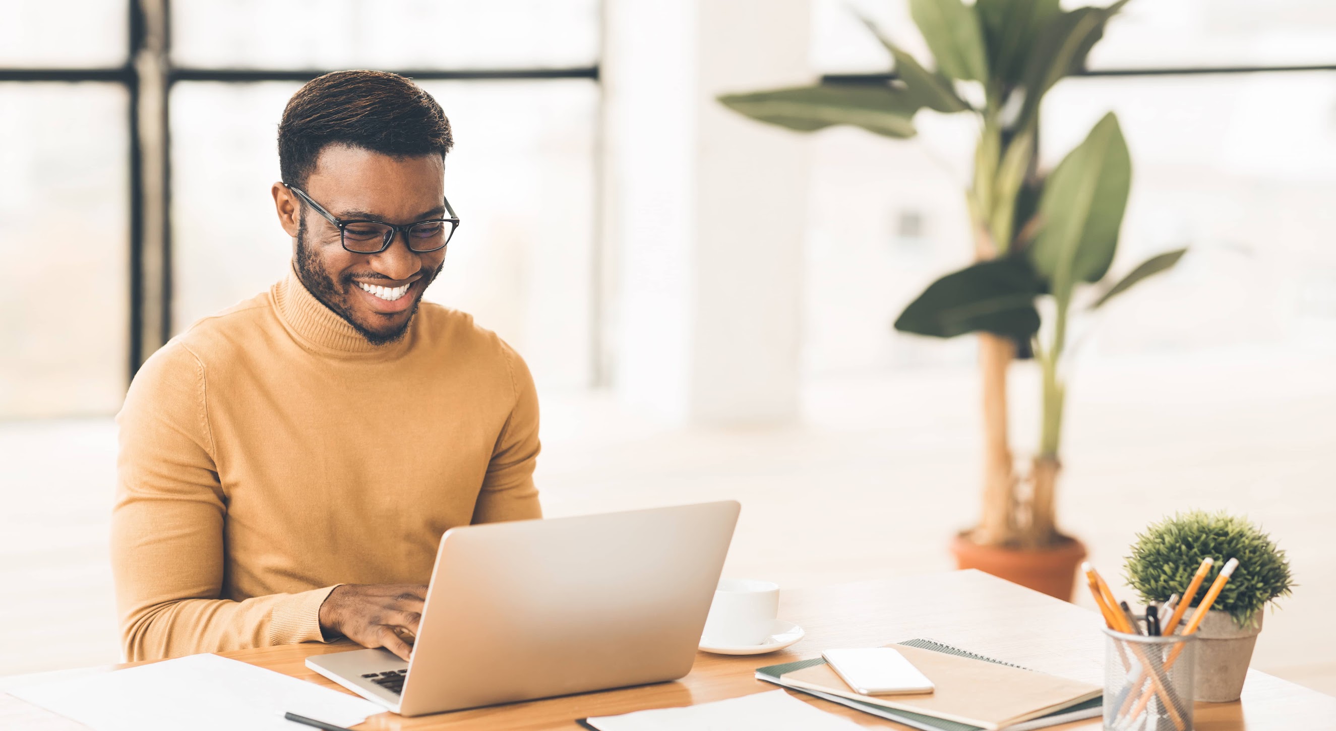 Happy man smiling and working on laptop in home office