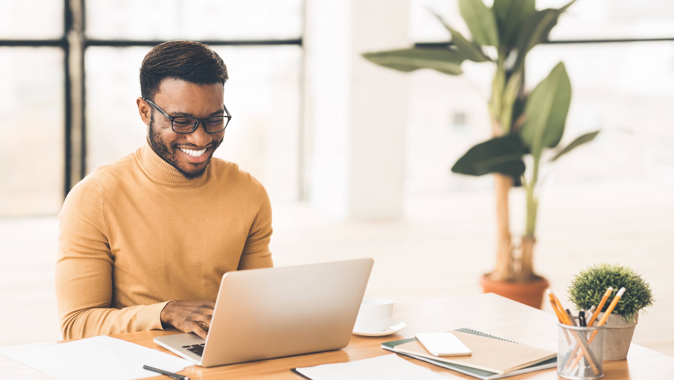 Happy man smiling and working on laptop in home office