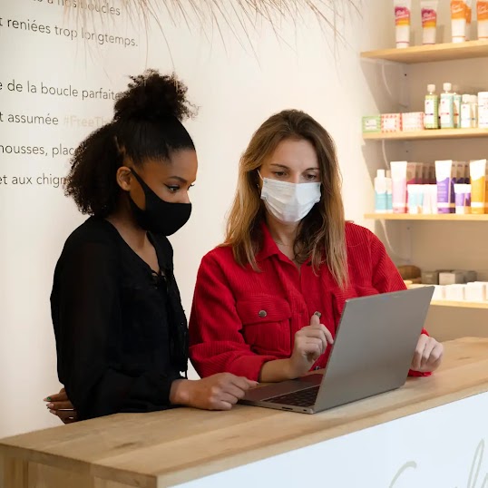 Deux femmes regardant un ordinateur dans un salon de coiffure