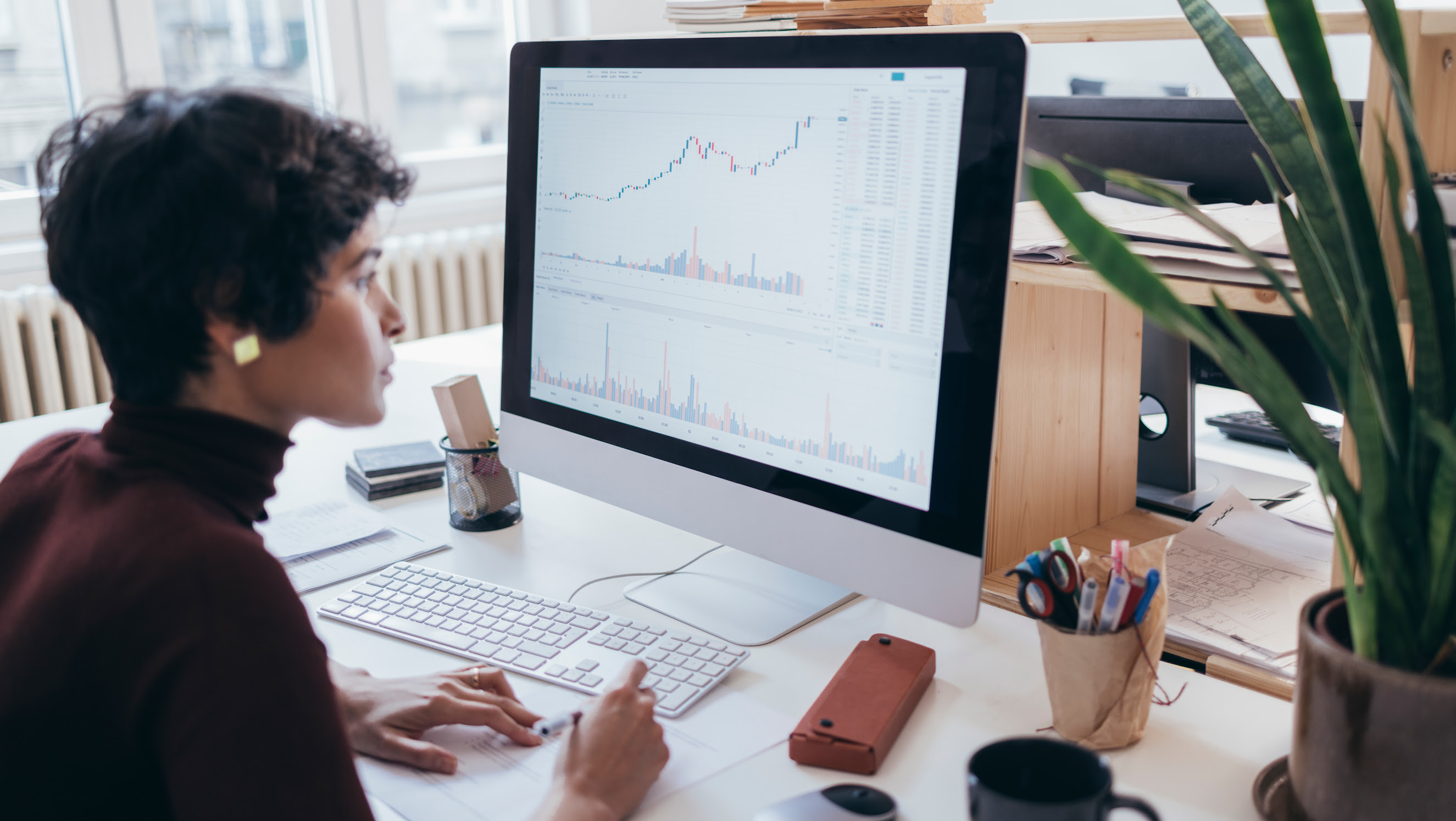 A female marketing expert looking at the screen of a computer and collecting information from the graphs and charts displayed.