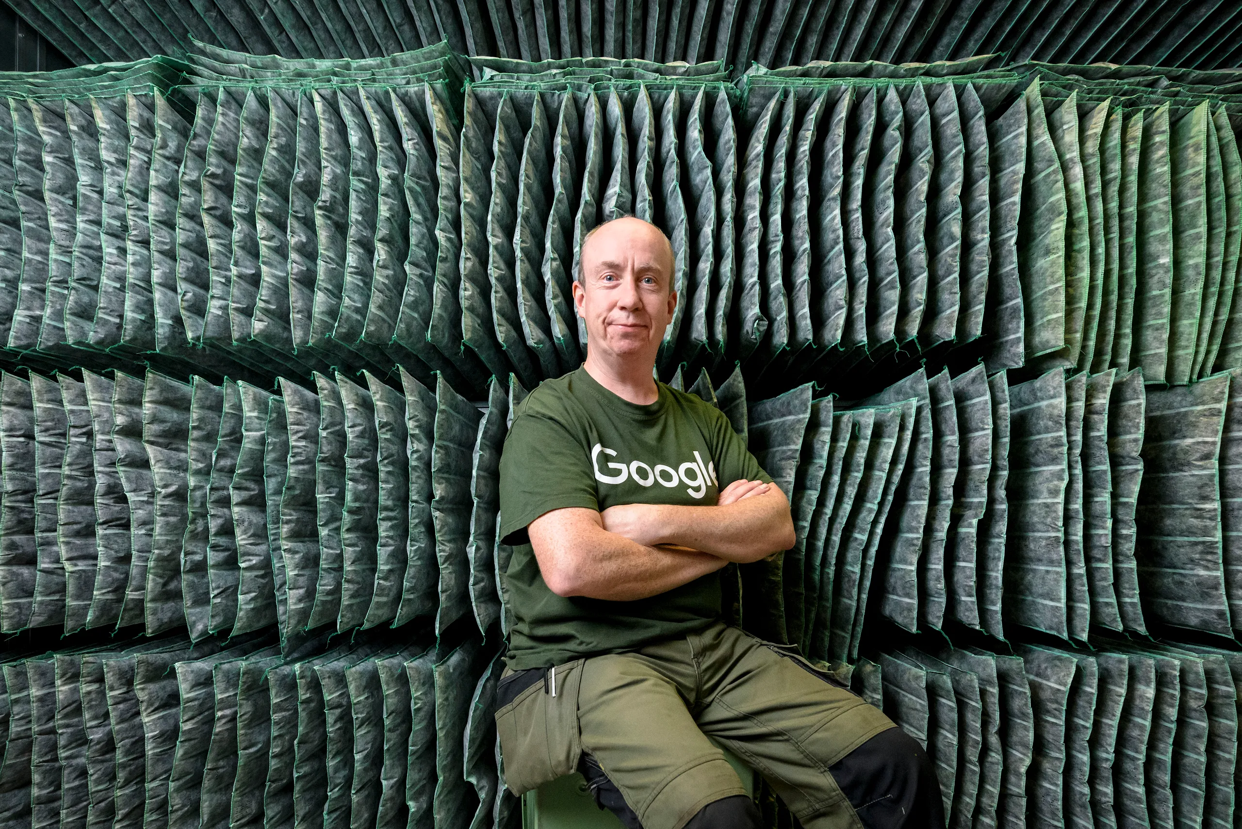 A photograph of a smiling man in a Google branded tshirt in a Google facility. 