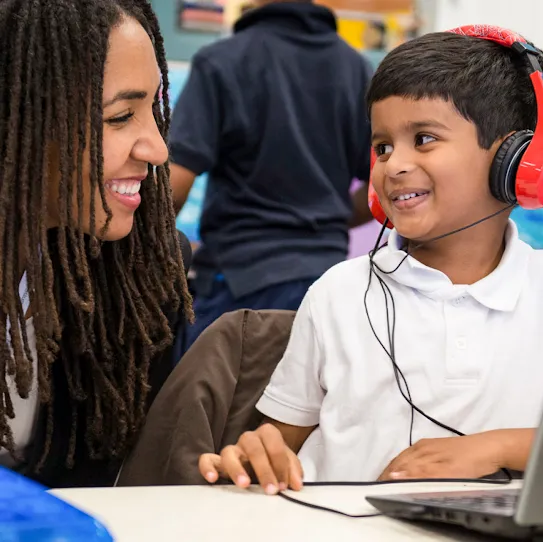 Inside a classroom, a teacher who participated in Google’s Global Teacher Training program works with a student on computer skills.