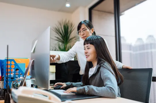 Two businesswomen working at a computer in an office.